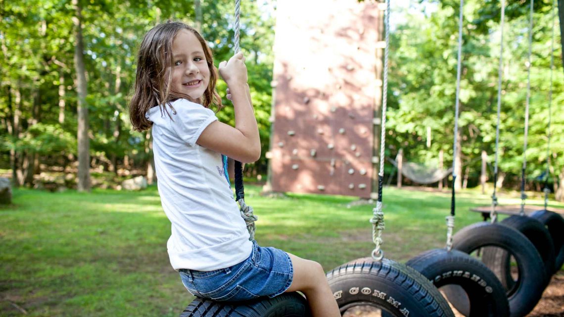 gallery-girl-sitting-on-tire – Deer Mountain Day Camp